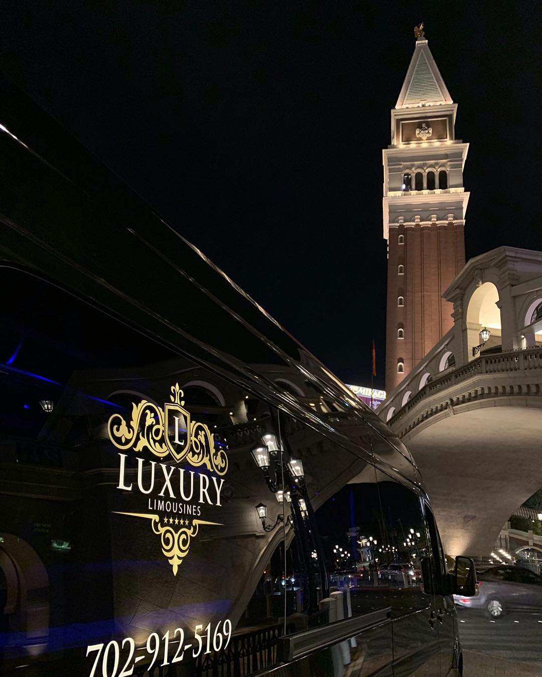 Branded luxury limo parked at night in front of the Venetian casino bell tower Las Vegas