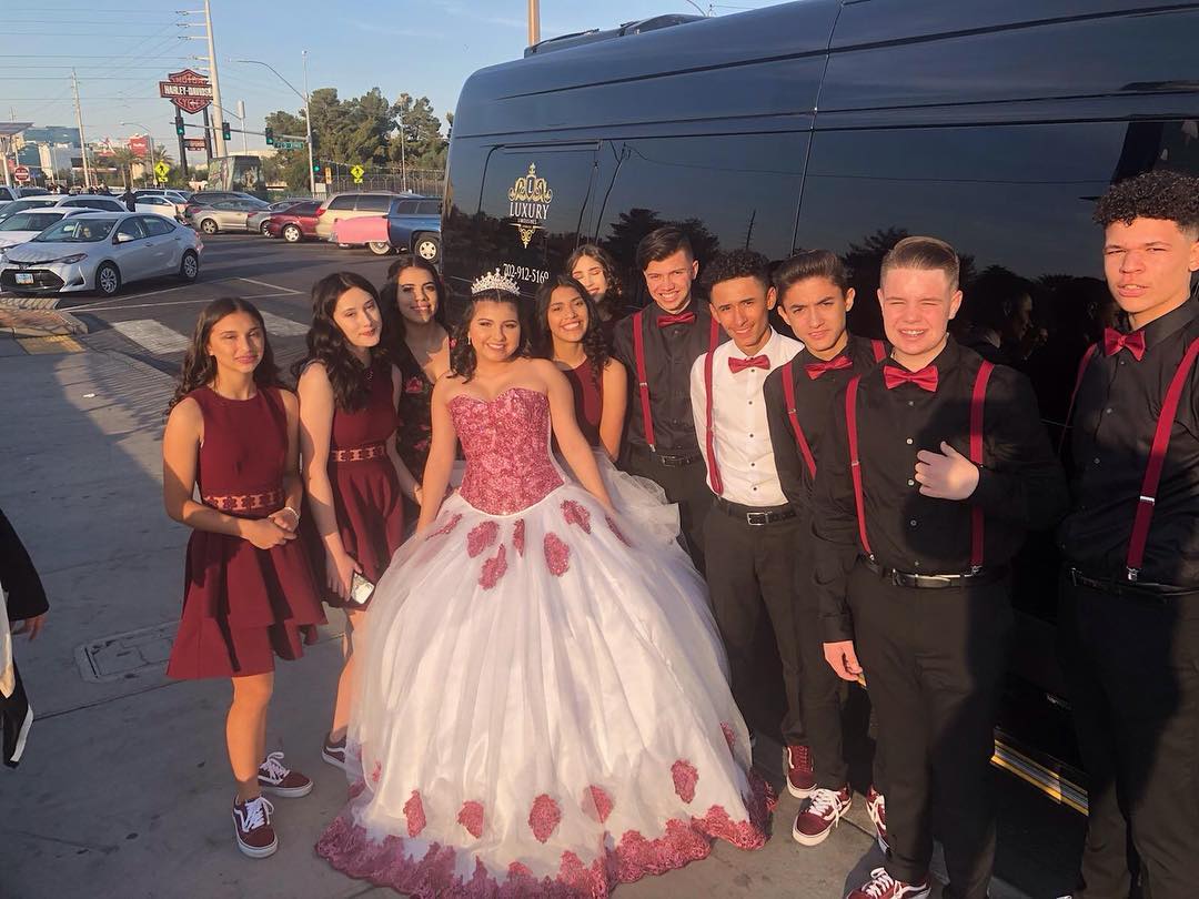 Quinceañera young woman in pink ball gown with full court of honor posing outside Las Vegas party bus