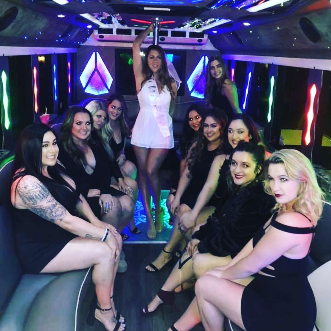 Group of women in black dresses inside a party bus with pink and purple LED lights Las Vegas bachelorette