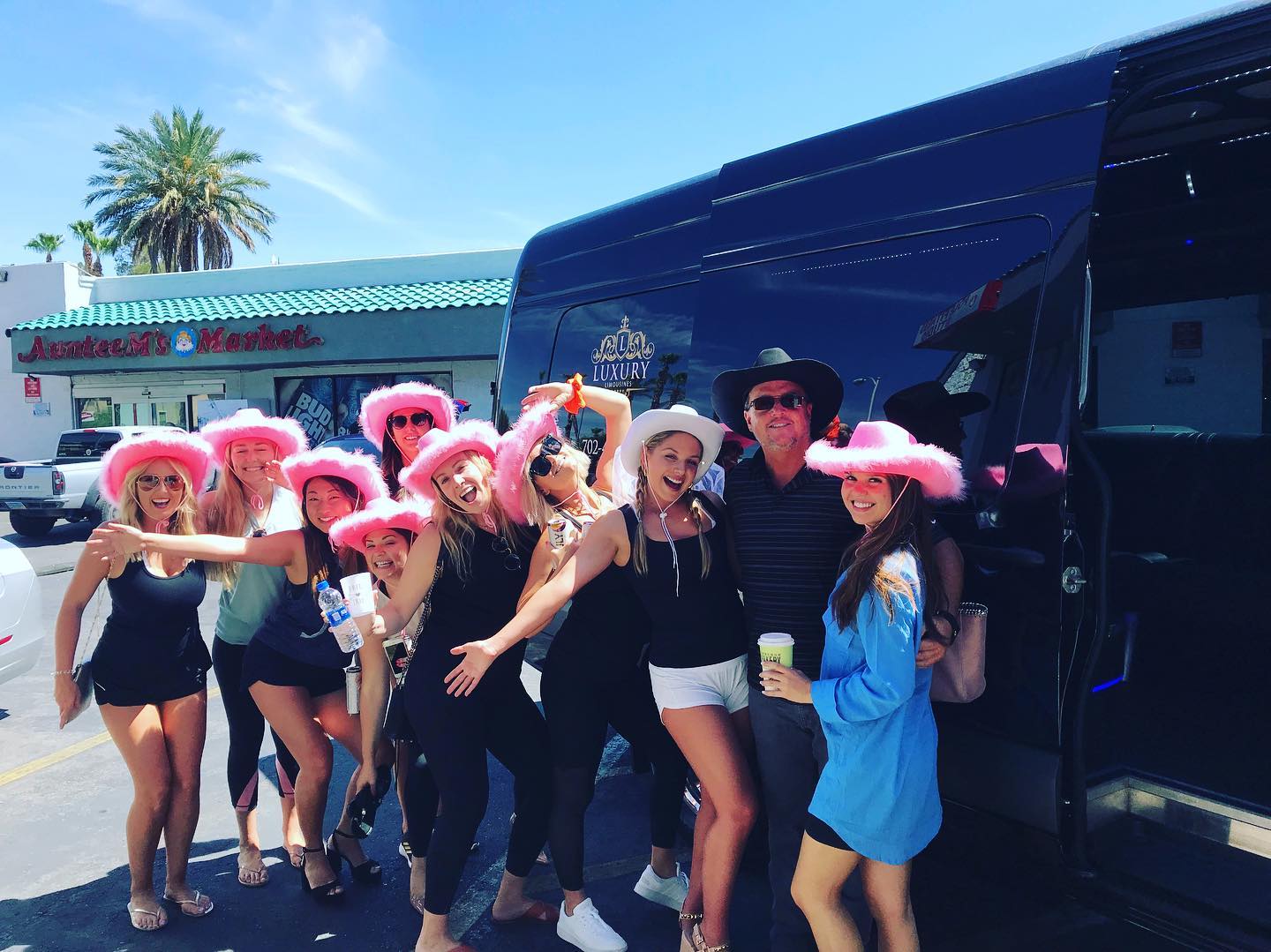 Women in pink cowboy hats celebrating outside a black party bus in Las Vegas daytime